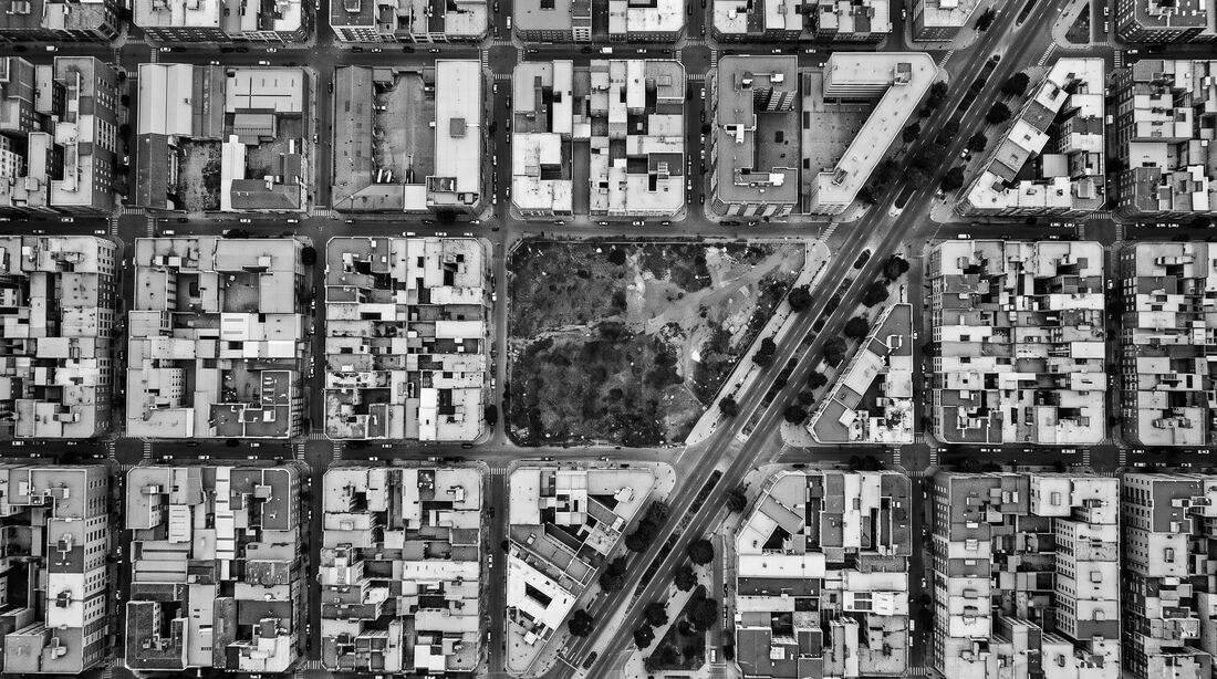 Vista aérea monocromática de una retícula urbana con un lote vacío al centro.